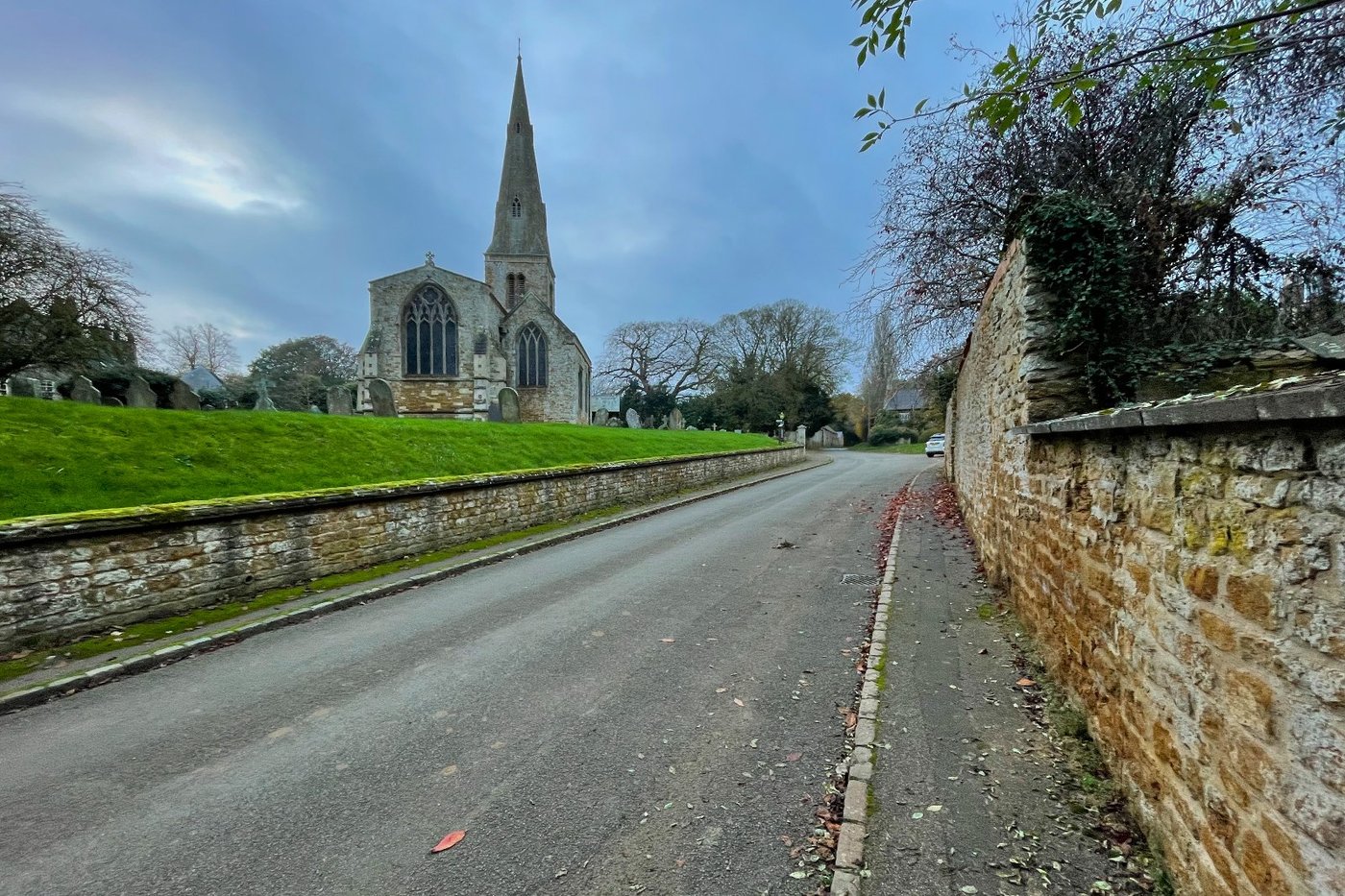 All Saints Church seen from Church Way, with the spire rising above the churchyard wall